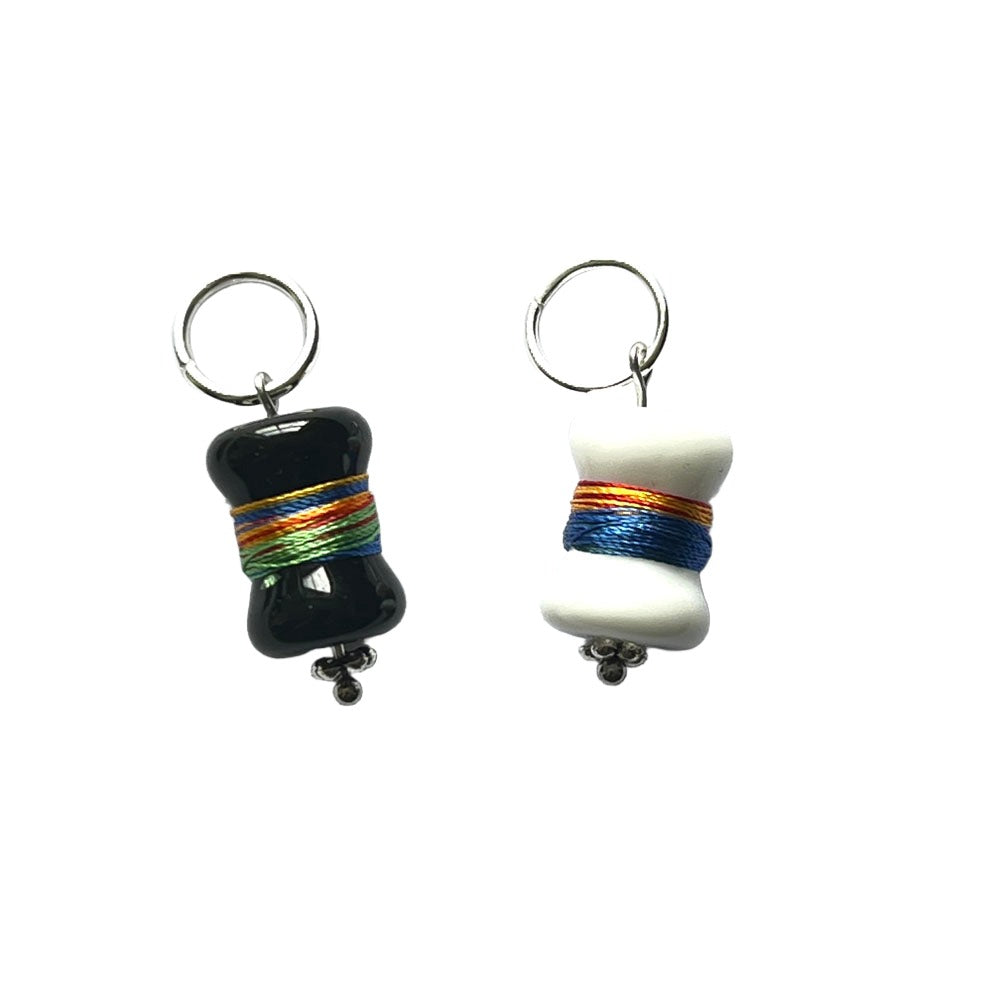 Black and white bobbin glass beads  wrapped with multicolour thread hanging from jump rings to create stitch markers.