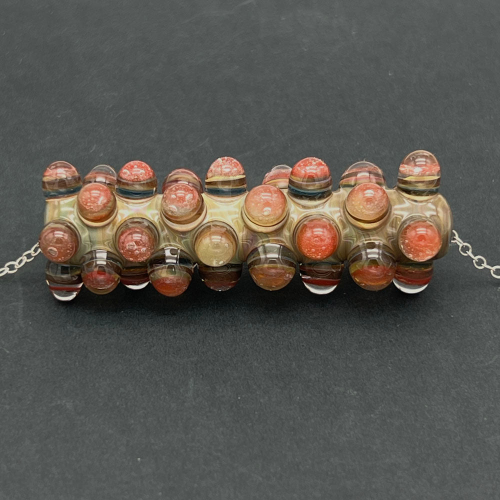 Close up of blossom raised bead necklace photographed on a dark background