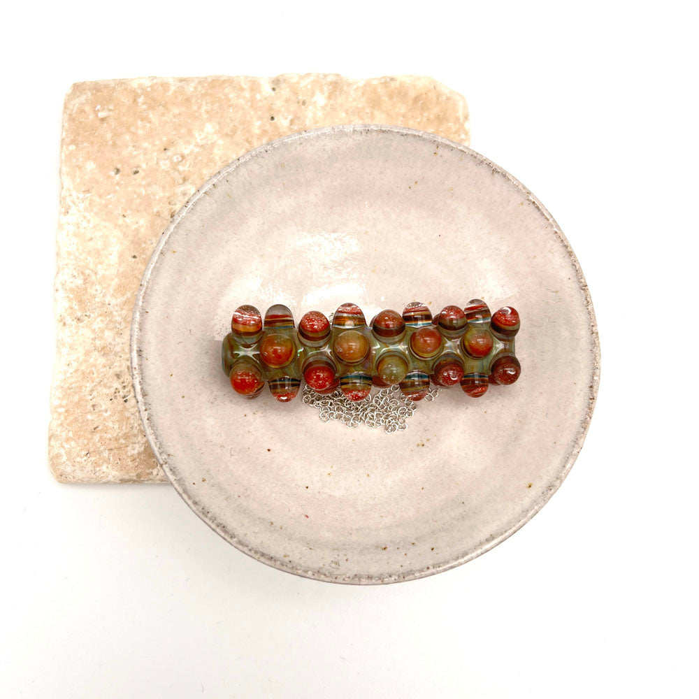Blossom bead necklace in a small white ceramic dish. Photographed from above.