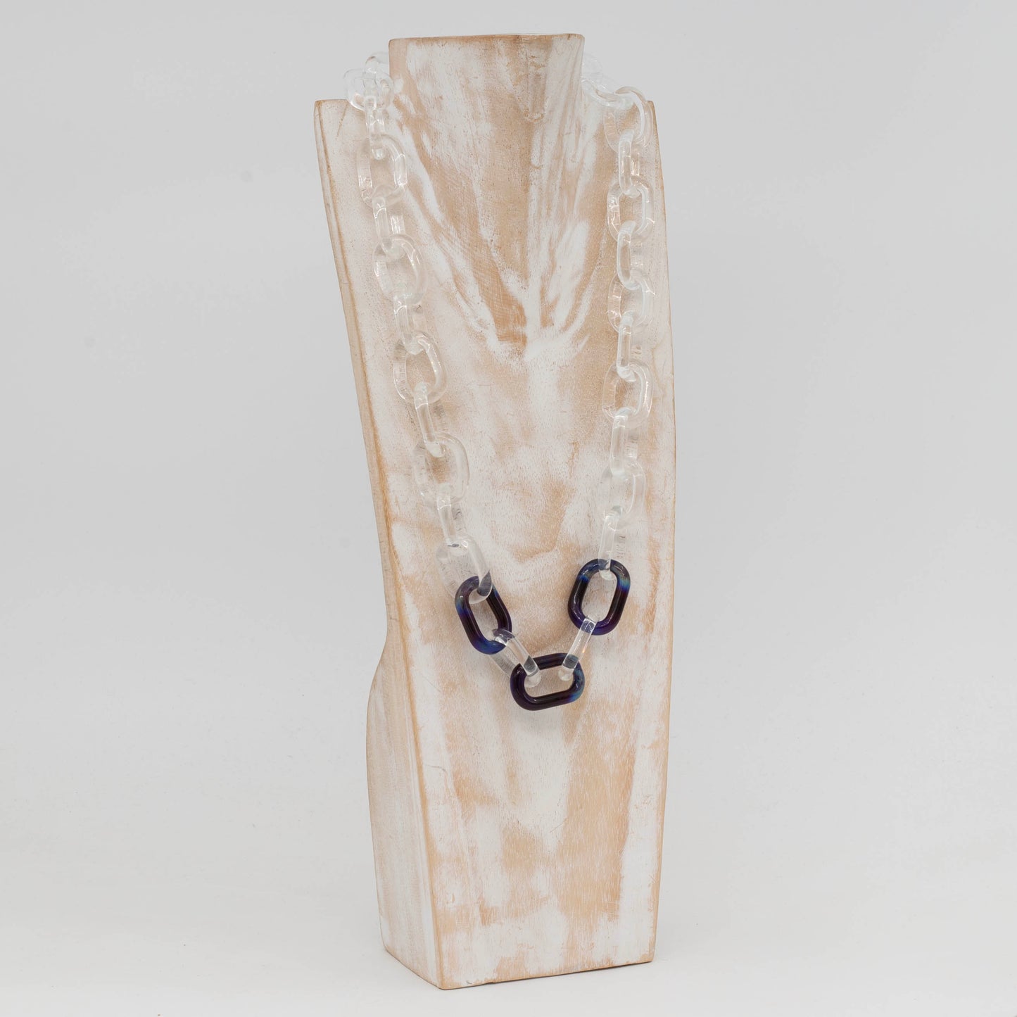 Side view of whitewashed wood torso showing clear glass necklace with three blue links