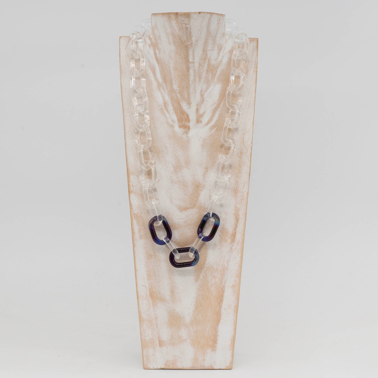 Front view of whitewashed wood torso showing clear glass necklace with three blue links