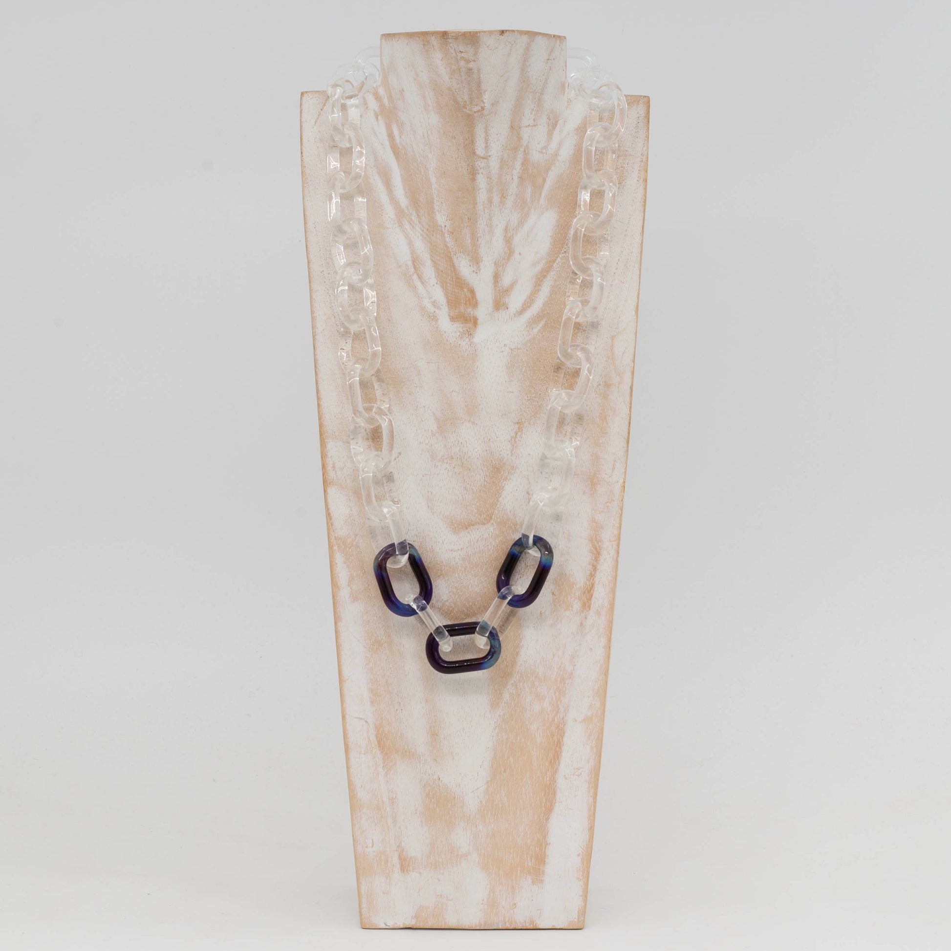 Front view of whitewashed wood torso showing clear glass necklace with three blue links