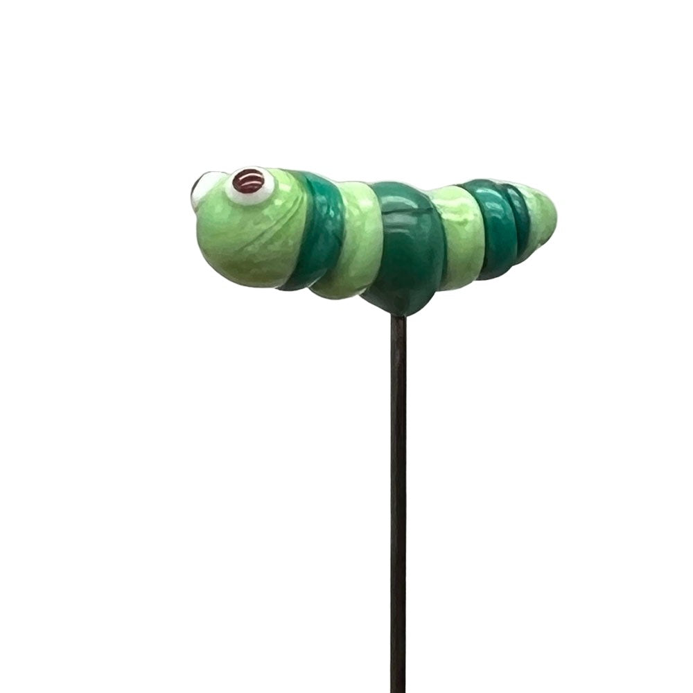 Side view of a handcrafted lampwork glass caterpillar pin, showing the detailed striping and elongated shape of the caterpillar.