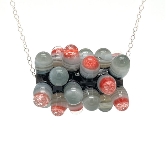 Close up of chunky rock bead hanging on a sterling silver chain against a white background.