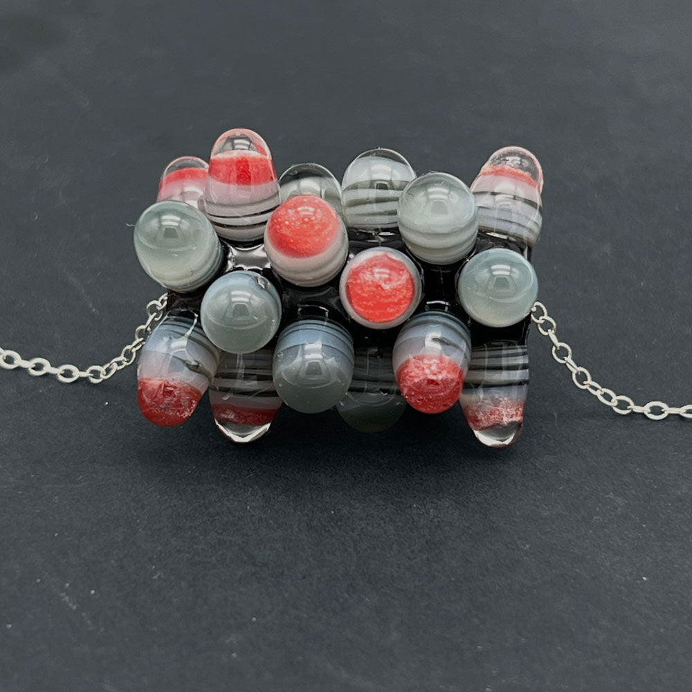 Close up of chunky rock bead showing raised dots made with layers of transparent black and white  topped with clear or orange and clear.