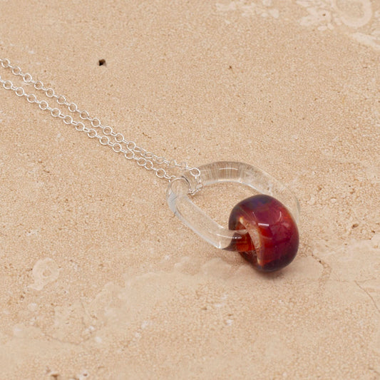 Sandstone tile, a necklace made with a clear link and pink barrel bead.