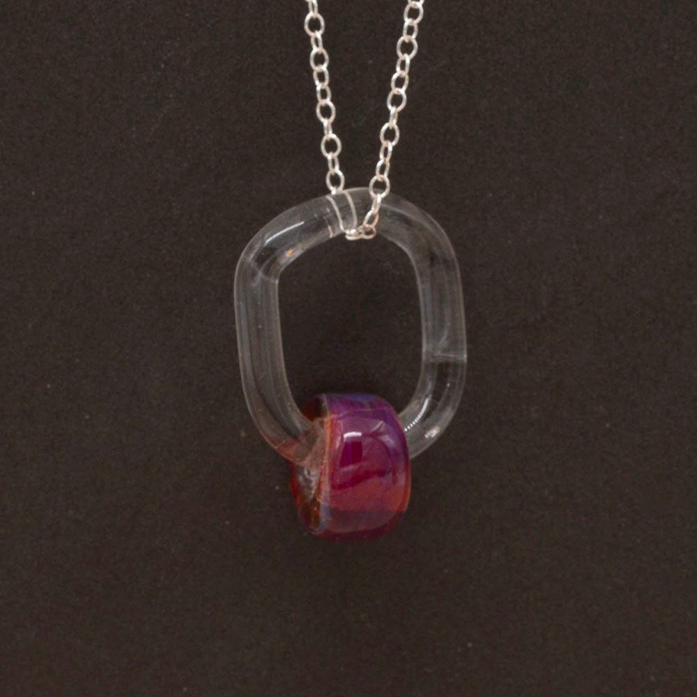 Close up, dark background,  a necklace made with a clear link and pink barrel bead.