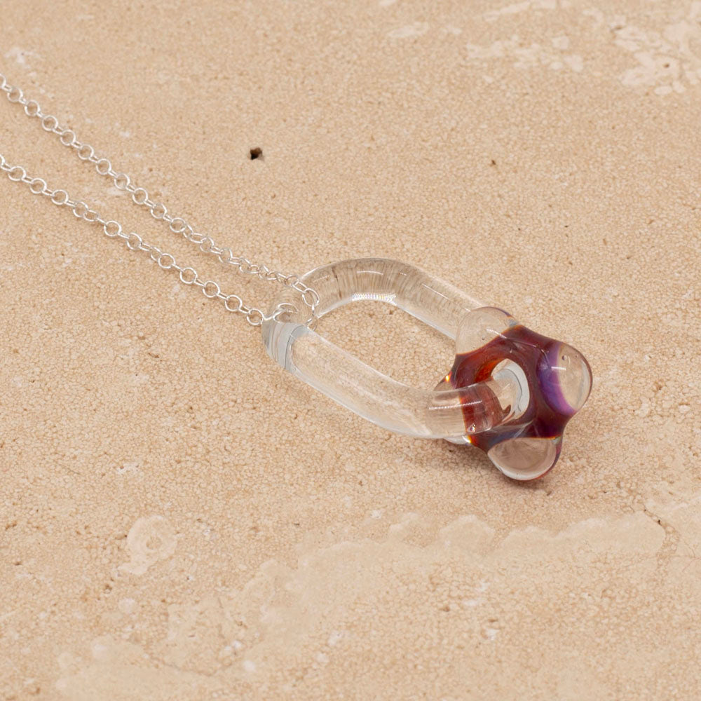 Sandstone tile and a necklace made with a clear glass link which passes through a pink bead.