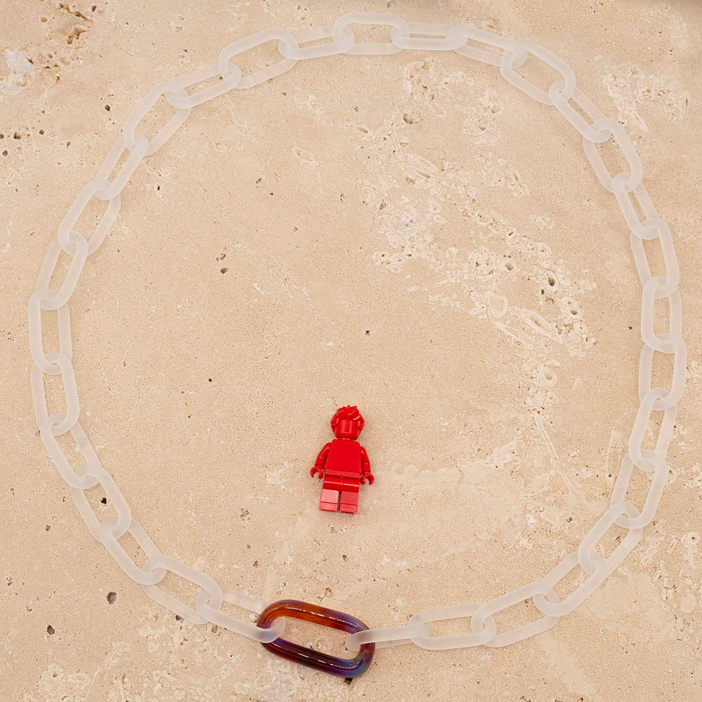 Necklace made from frosted glass links with  single multi colour link. Photographed with a Lego figure for scale.