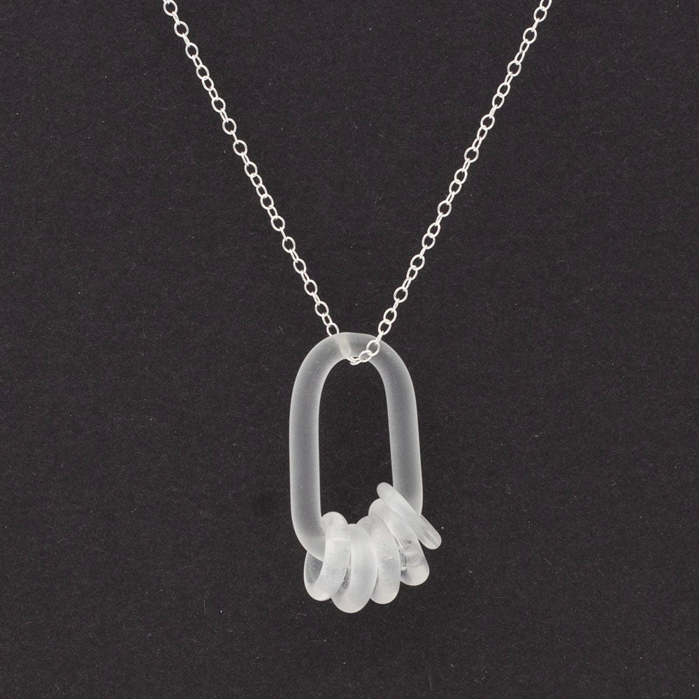 Close up of a clear glass link which passes through five clear glass beads. Both beads and link have a frosted finish.