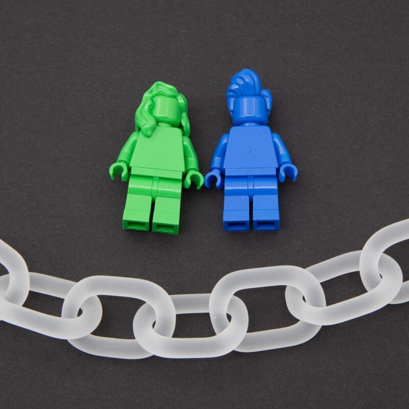 Close up of clear frosted glass chain link necklace photographed with Lego figured for scale