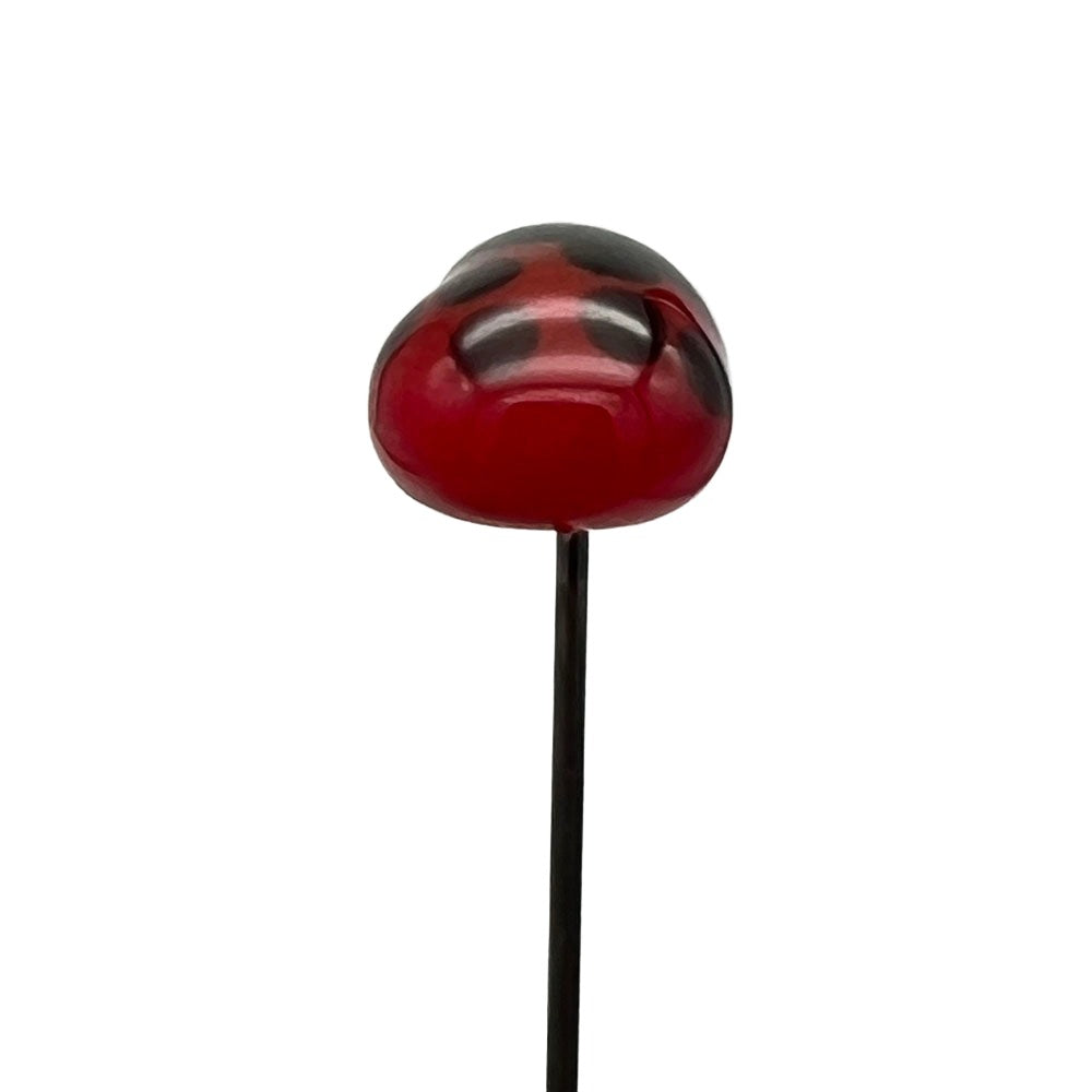 Handmade glass ladybird pin with a red body and black spots, back view, on a stainless steel pin