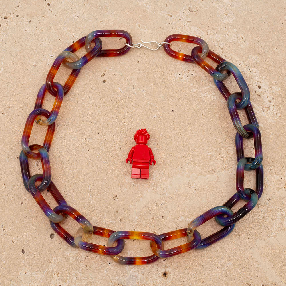 Chunky necklace made from multicolour mai tai glass links, photographed from above with a Lego figure for scale
