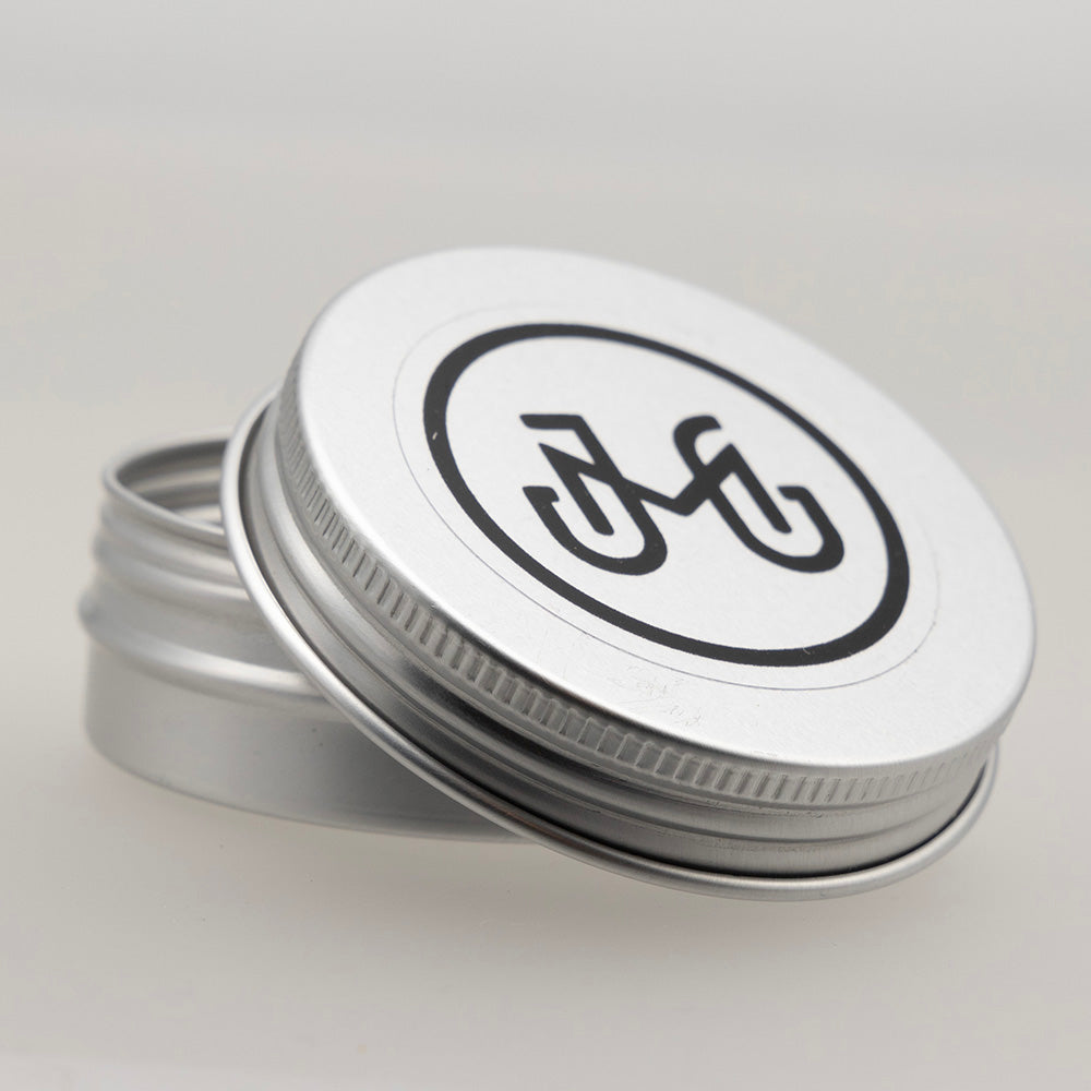 round metal tin with screw on lid and Joy McMillan Glass logo