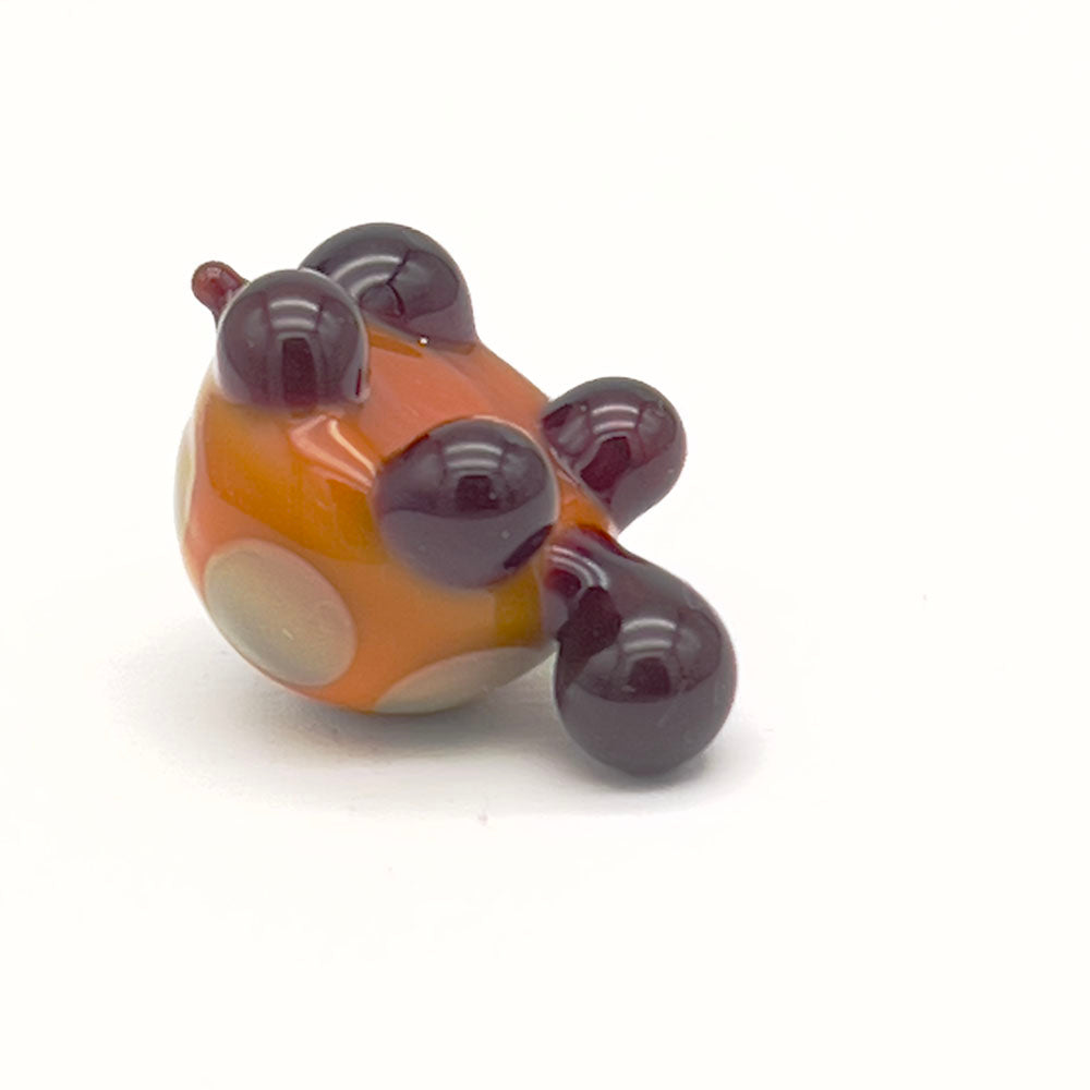 The underside of a yellow and grey glass tortoise with light grey spots, showing its four legs and tail.