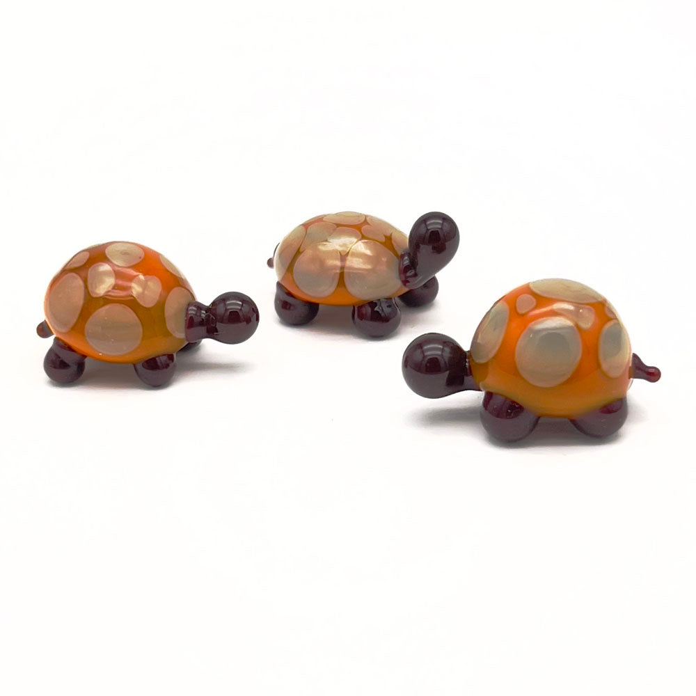 Three yellow and grey glass tortoises with light grey spots grouped together.