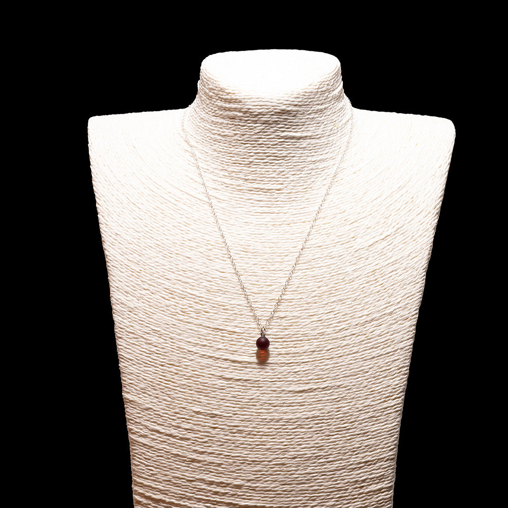 red glass ball charm necklace with sterling silver chain shown on a white mannequin bust