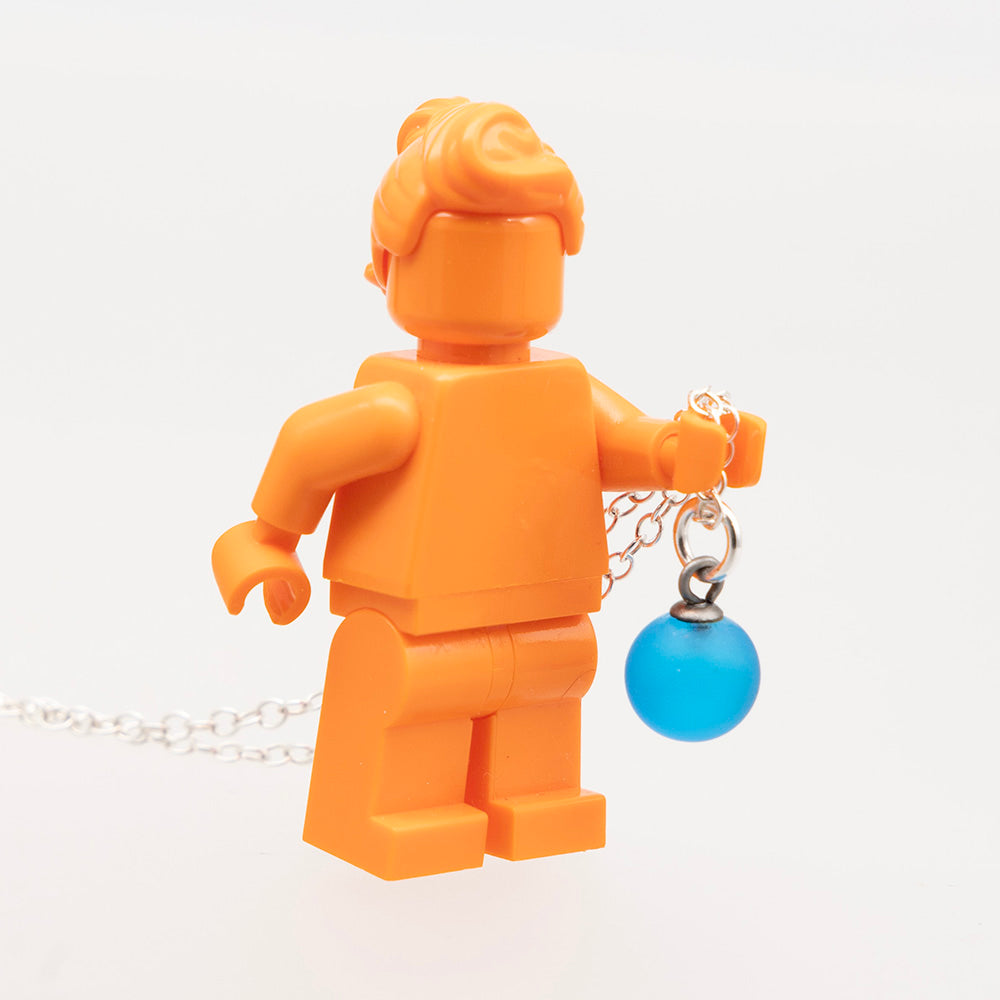 Glass ball necklace held by orange lego mini figure to show scale. The glass charm is approximately half the height of the legs.