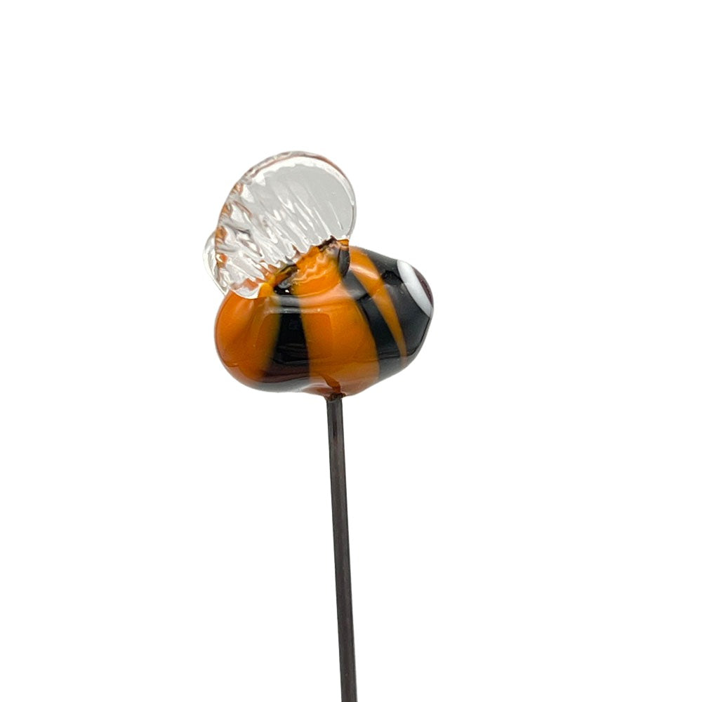 Side view of the handmade lampwork glass bee plant decoration, showcasing its yellow and black striped body and clear glass wings, against a plain background