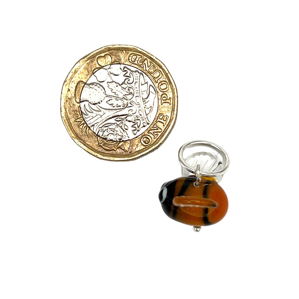 Bee Stitch Marker with Jump Ring and Pound Coin for Scale  Image of a handmade glass bee stitch marker next to a British one-pound coin for size comparison. The bee features a yellow and black striped body, black head with white eyes, and clear wings, attached to a silver jump ring.