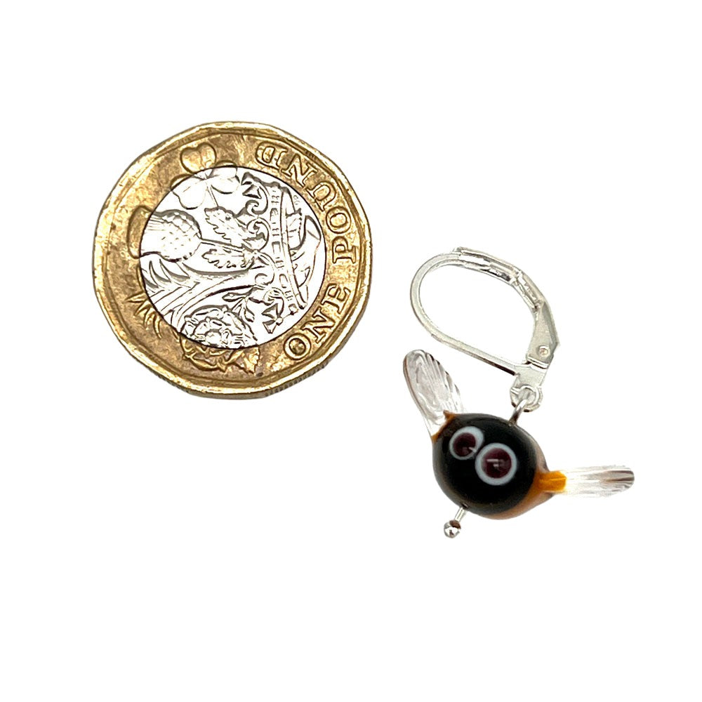 Bee Stitch Marker with Latch Back Hook and Pound Coin for Scale  Image of a handmade glass bee stitch marker with a latch back hook next to a British one-pound coin for size comparison. The bee has a yellow and black striped body, black head with large white eyes, and clear wings.