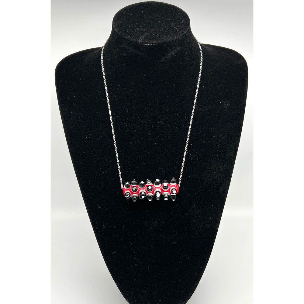 Black velvet bust displaying a necklace with red, black and white glass bead