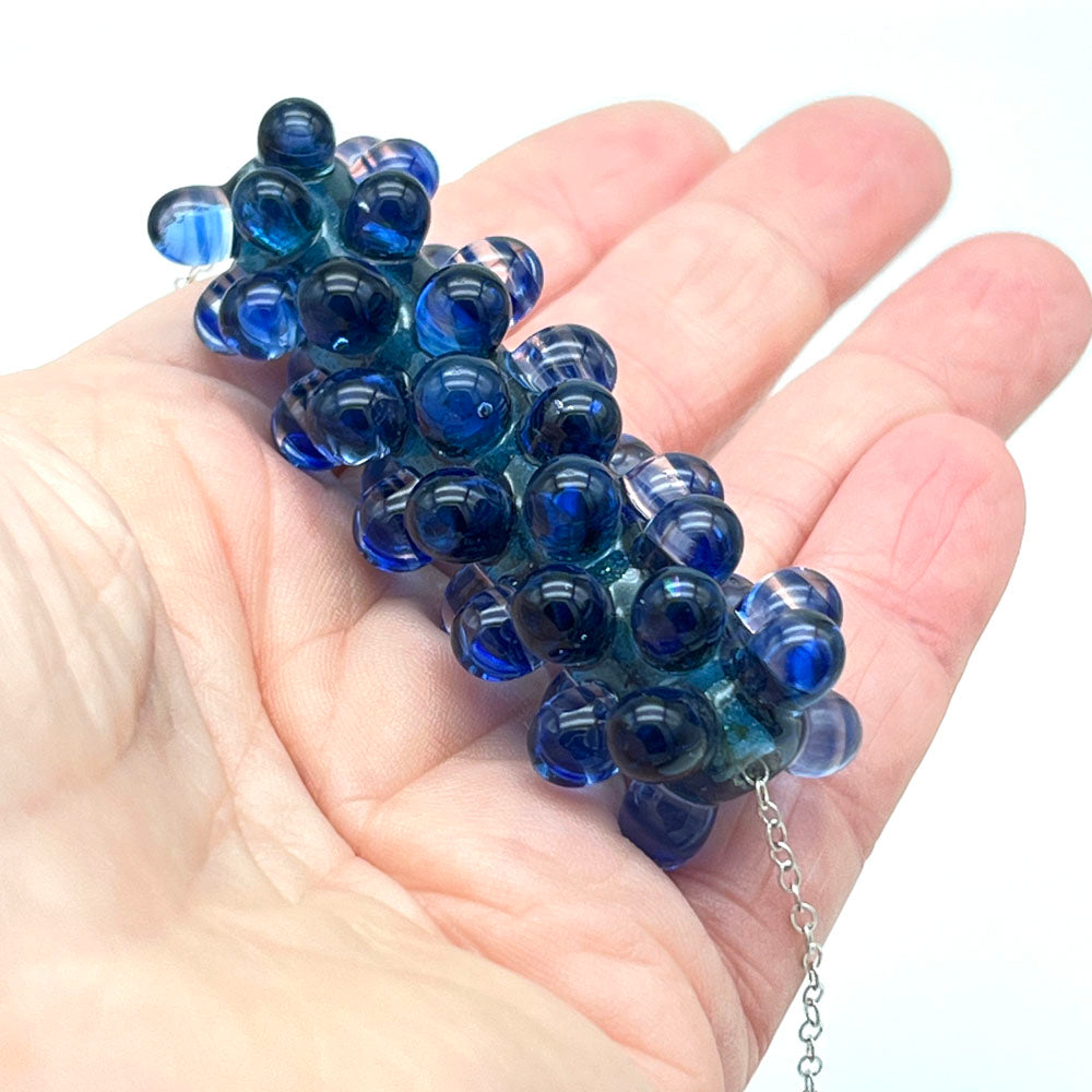 blue ripples glass bead necklace held in the palm of a hand.