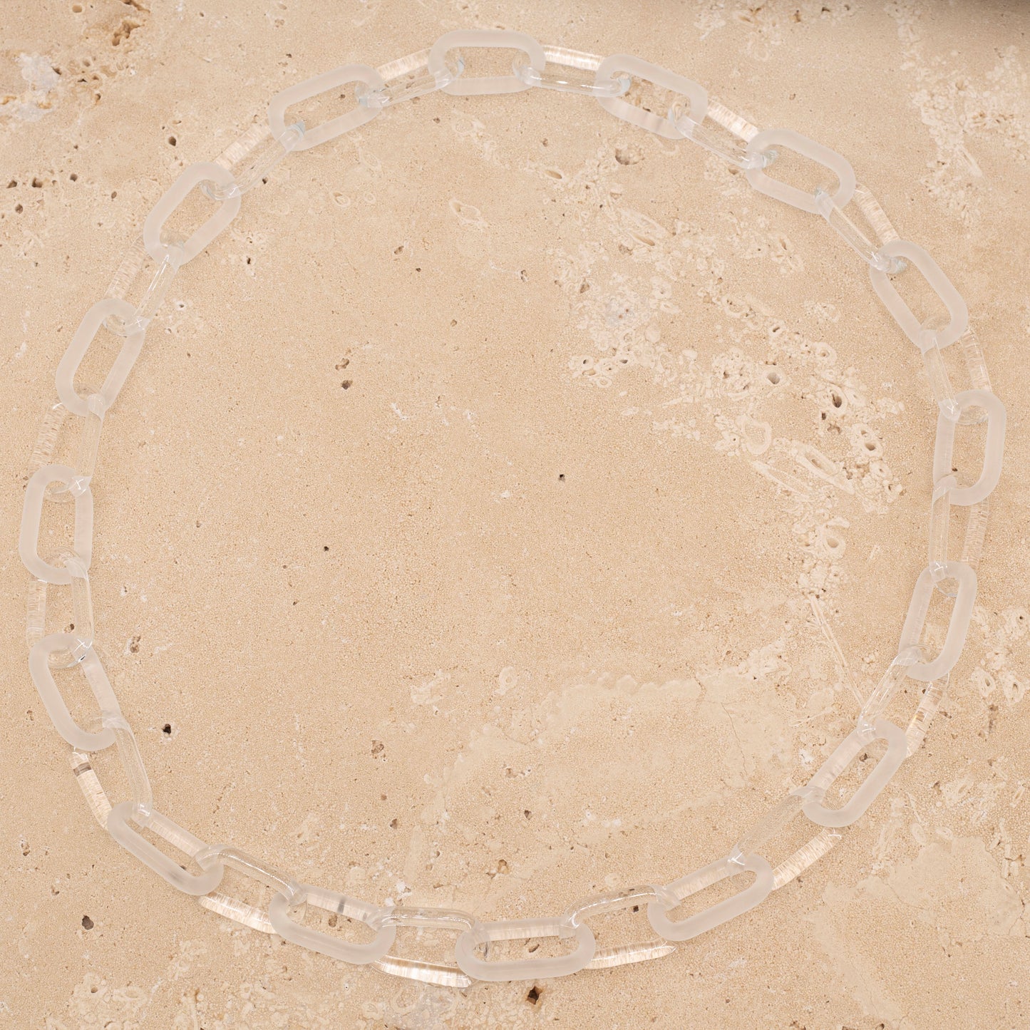 Overhead view of glass necklace made with bold links of alternating clear and frosted glass