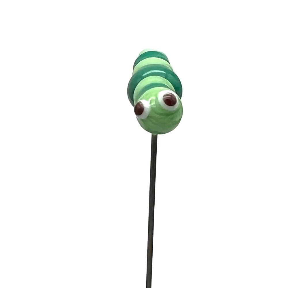 A glass caterpillar plant decoration on a stake, viewed from the front, with large brown eyes and light and dark green stripes.