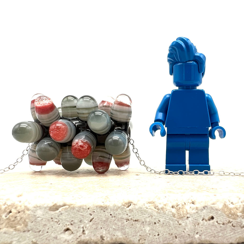 chunky rock bead on chain shown beside a blue Lego figure for scale. The bead comes to just below the figures shoulder.