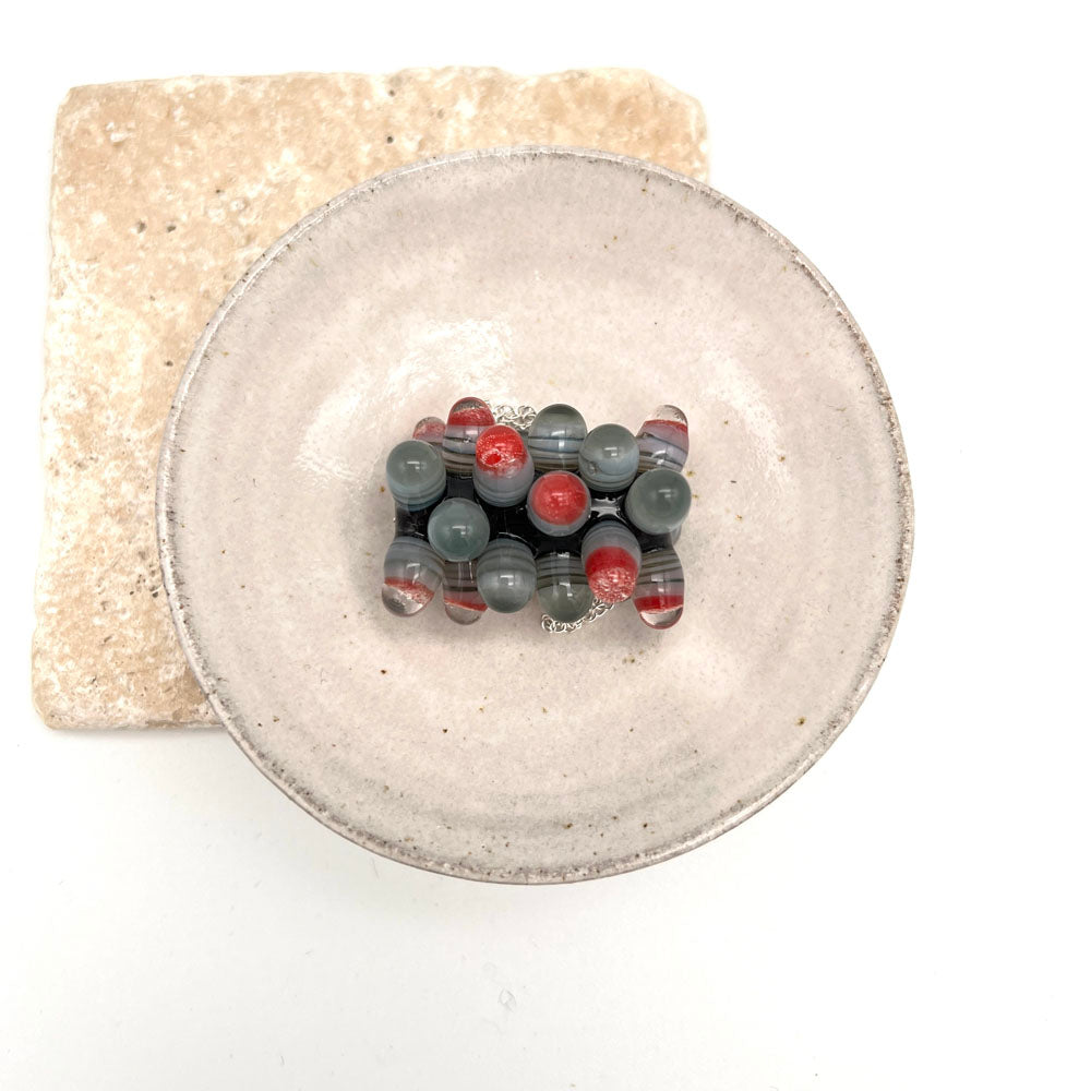 chunky bead with raised dots sitting in a small white ceramic bowl. Photo taken from overhead.