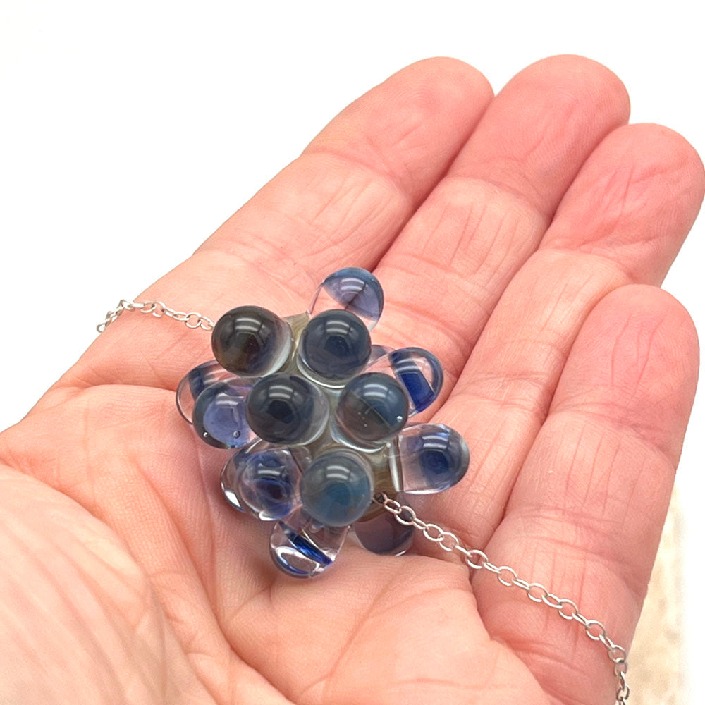 Pebble Beach glass bead necklace shown in the palm of a hand.