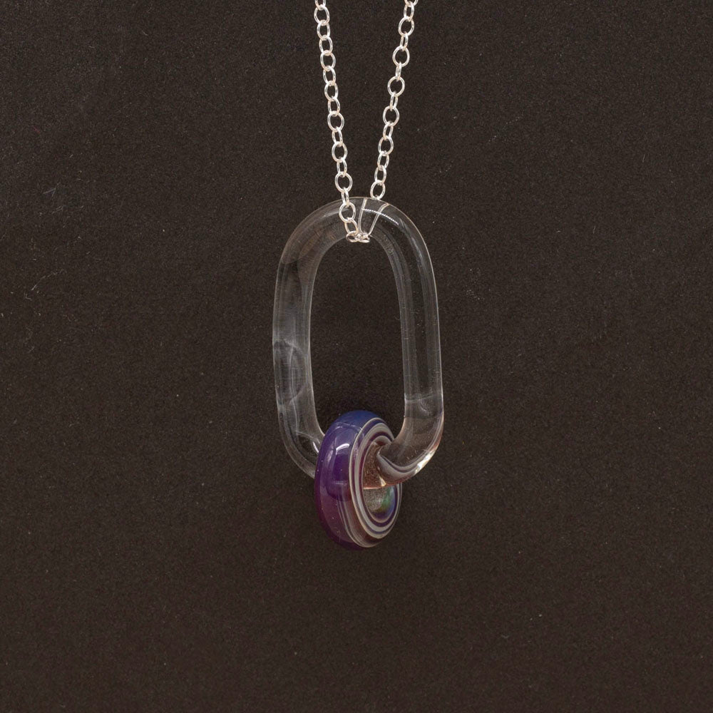 Close up of clear glass link with purple iris bead.