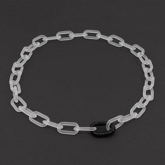 A clear frosted glass chain necklace with a single shiny glass link on a dark background