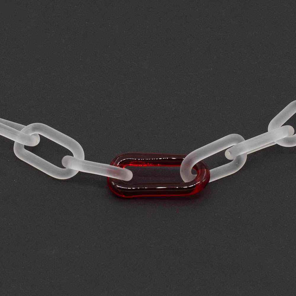 Close up of frosted glass chain with single red link, dark background