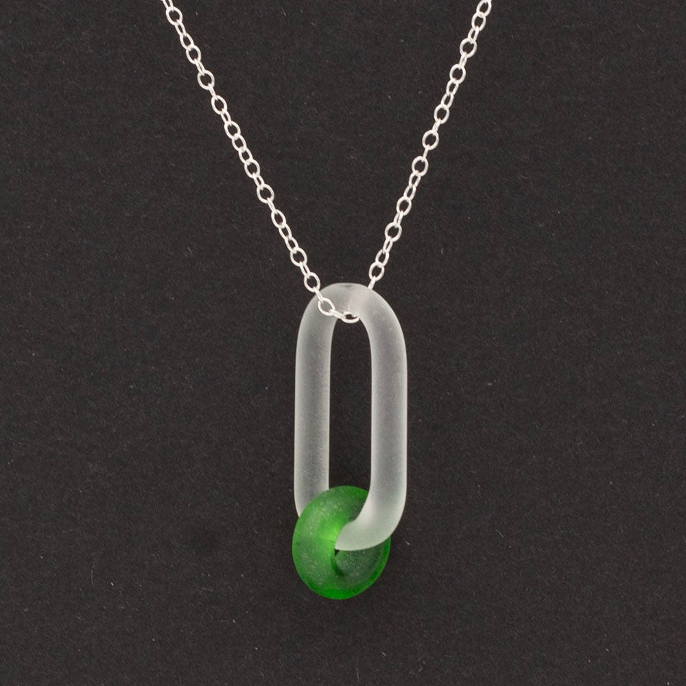 Dark background. Close up of  frosted clear glass link and green gin bottle glass bead necklace.