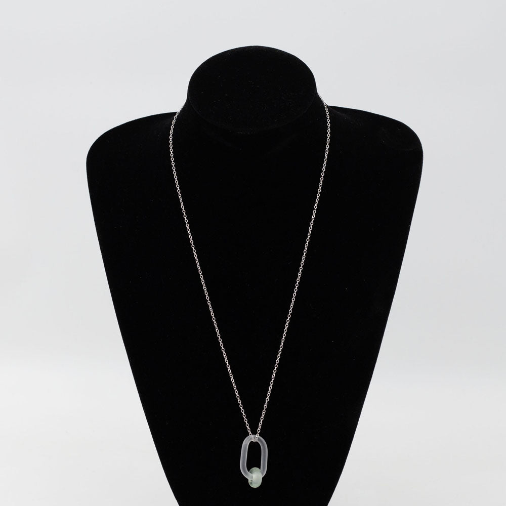 Black velvet bust displaying a clear link which passes through a bead made from a recycled pale green wine bottle. Link and beads have a frosted finish. The link hangs from a sterling silver chain.