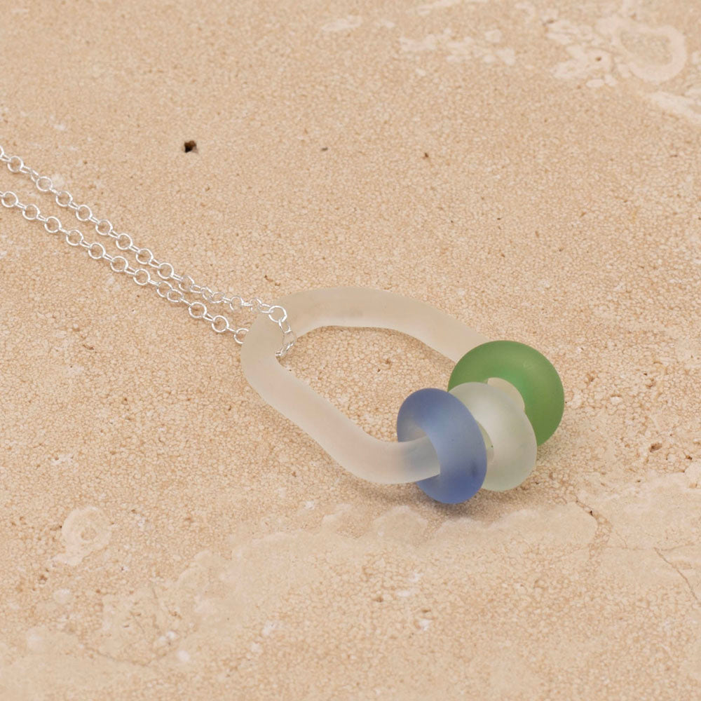Sandstone tile with clear link which passes through beads in blue, green and clear glass. Link and beads have a frosted finish. The link sits on a sterling silver chain.  