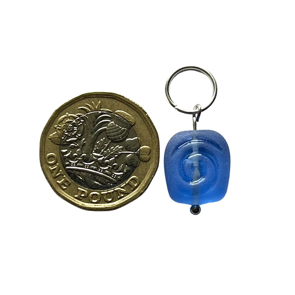 blue spiral stitch markers on jump ring fastening shown with a pound coin for scale.