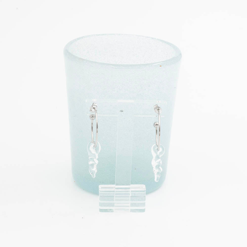 stainless steel hoop earrings with small glass icicle drops, shown in front of an ice blue tumbler