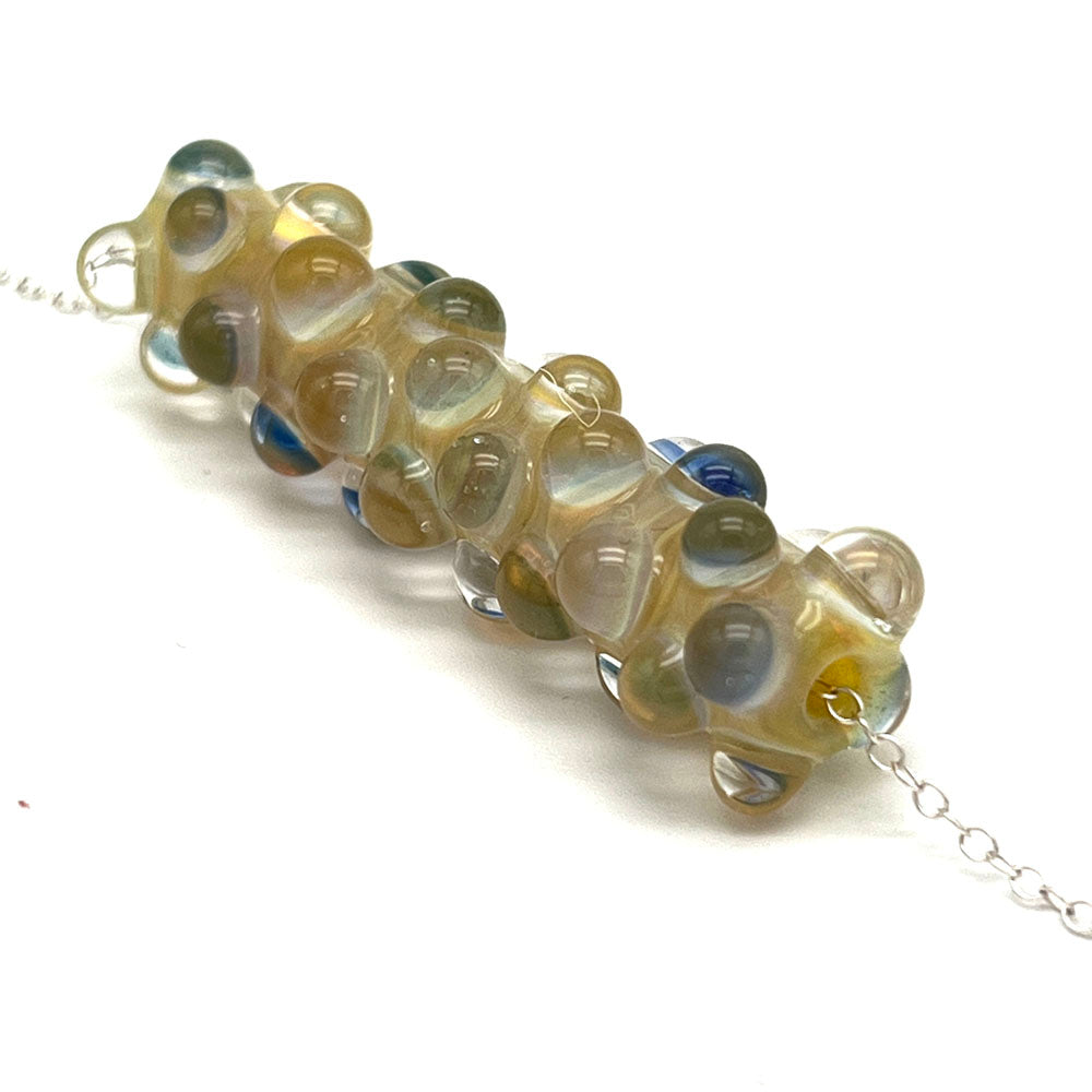 End view of lemonade bead necklace showing how the dots with blue layers spiral along the length of the bead.