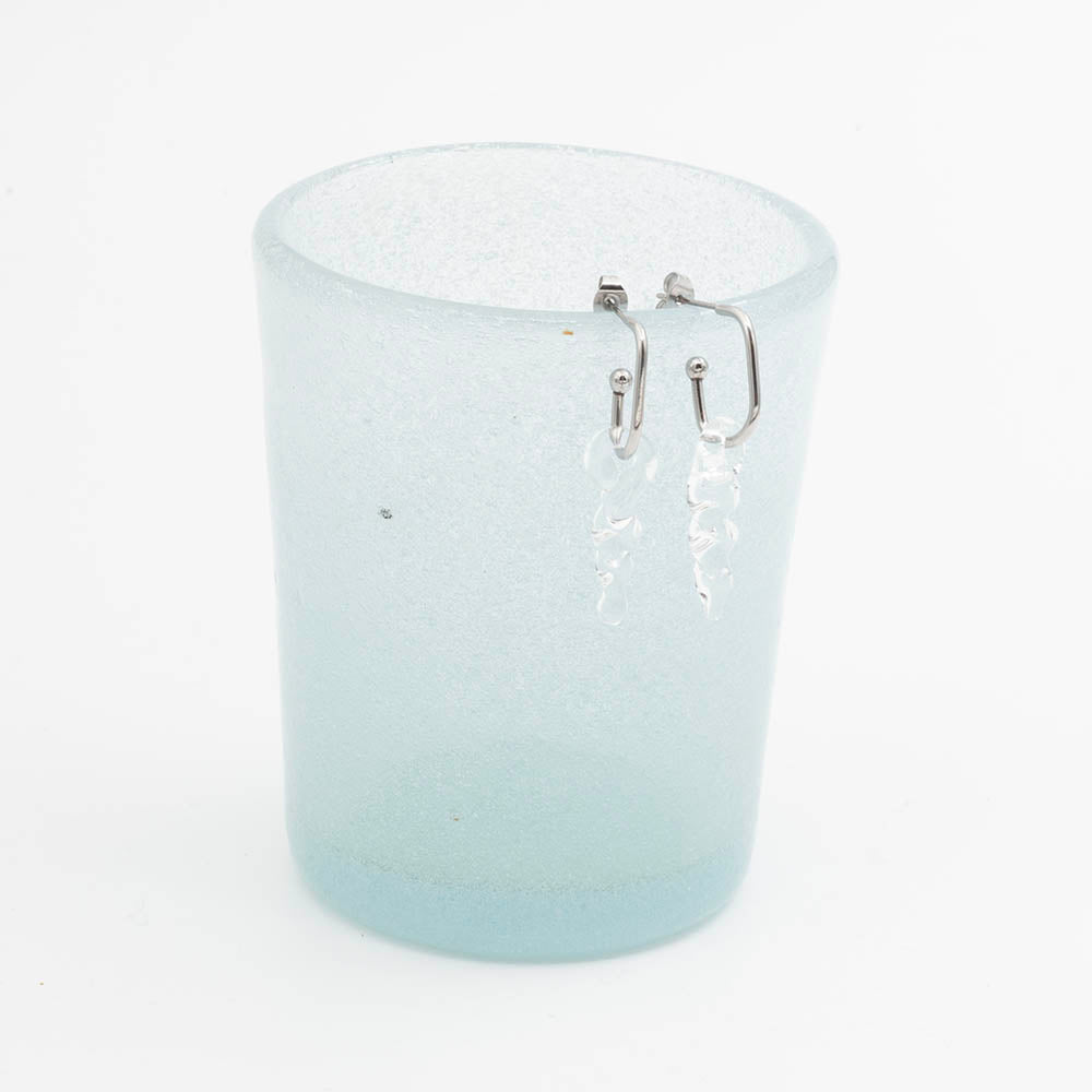 oval hoop earring with small glass icicle drops on the edge of a blue tumbler