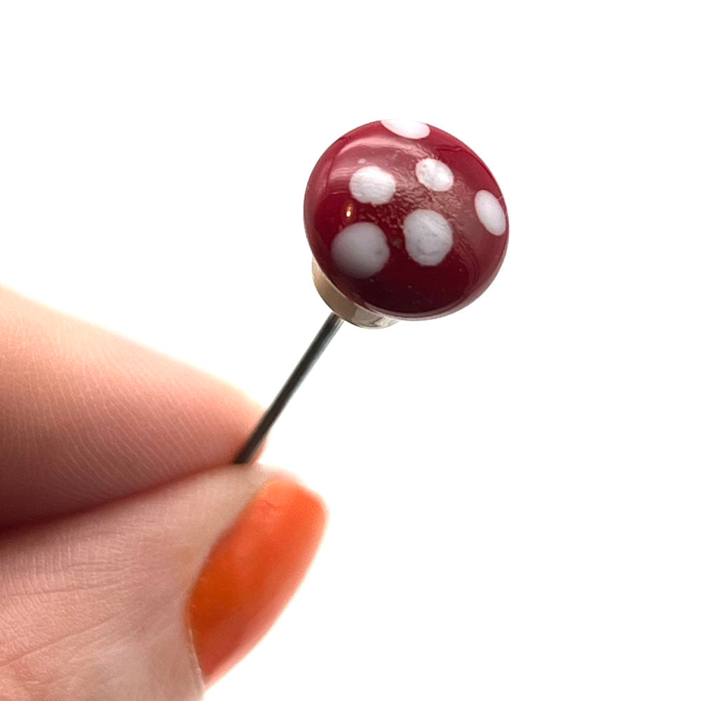 Top view if mushroom pin showing rounded red cap with white dots. 