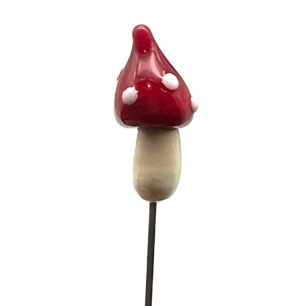 Glass pin topped with a glass mushroom. The mushroom has a cream stalk and red cap with raised white dots. The cap is pointed.