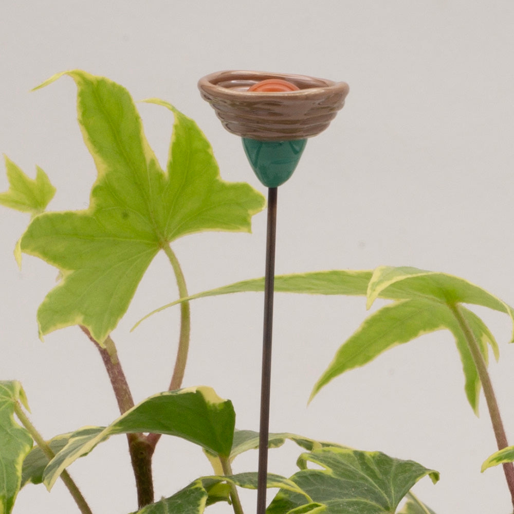 close up of purple flower decoration showing green stalk, purple cup and yellow centre