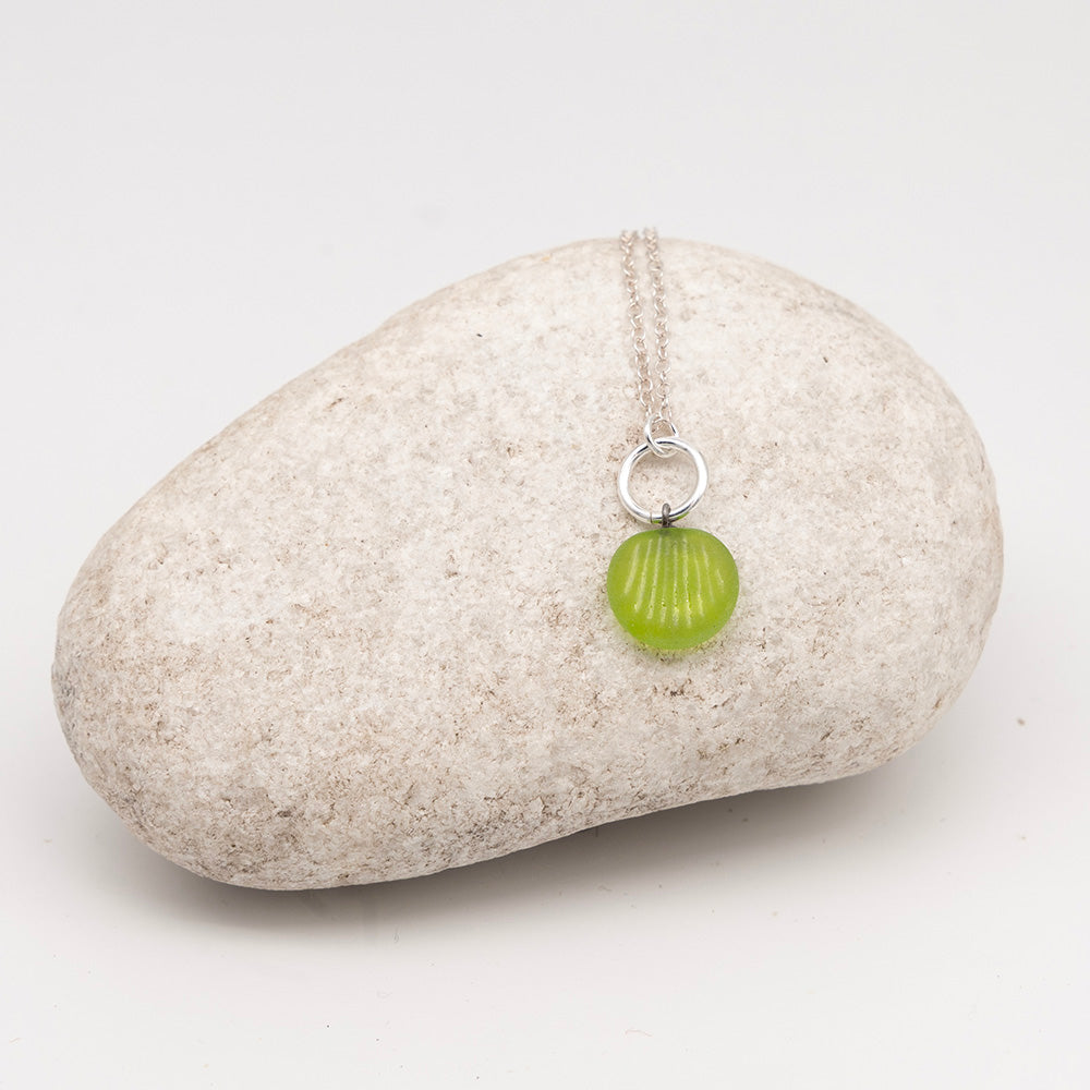 frosted lime green glass shell charm necklace on a pale grey rock