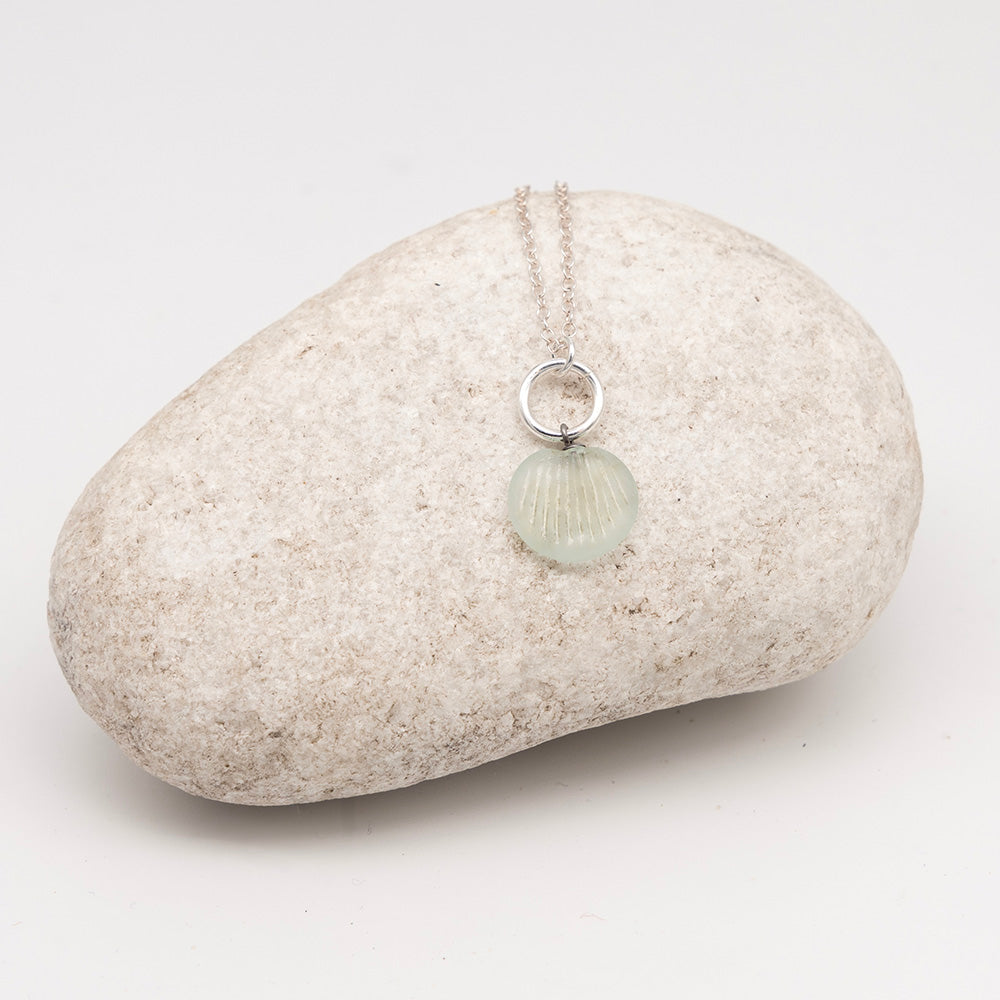 frosted pale blue glass shell charm necklace on a pale grey rock