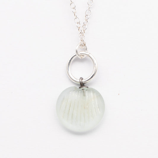 Close up of pale blue frosted glass charm with shell imprint on a plain white background. The charm is frosted, and spiral is shiny. The charm hangs on a large silver jump ring. The necklace is completed with a small silver jump ring and silver chain.