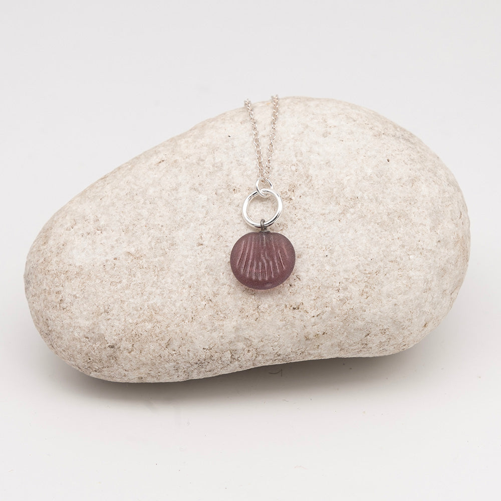 frosted purple glass shell charm necklace on a pale grey rock