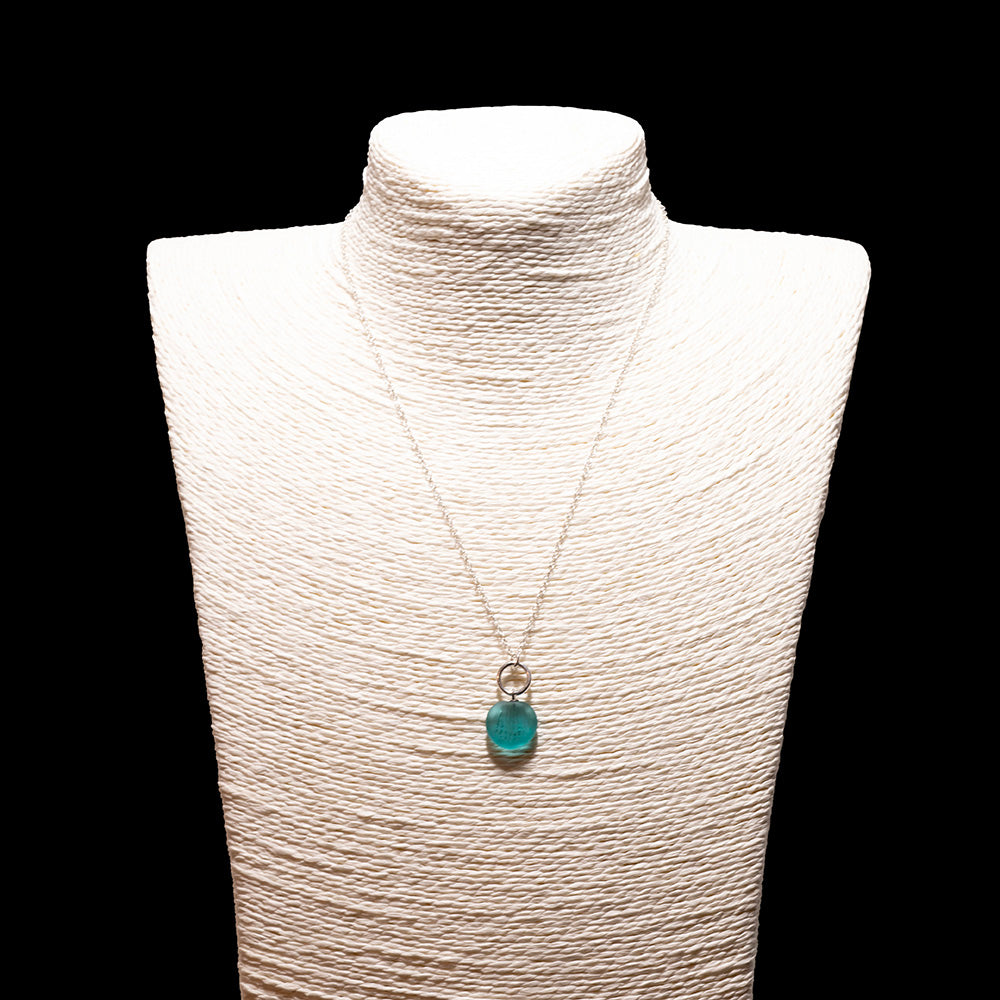 teal frosted glass shell imprint charm necklace with sterling silver chain shown on a white mannequin bust